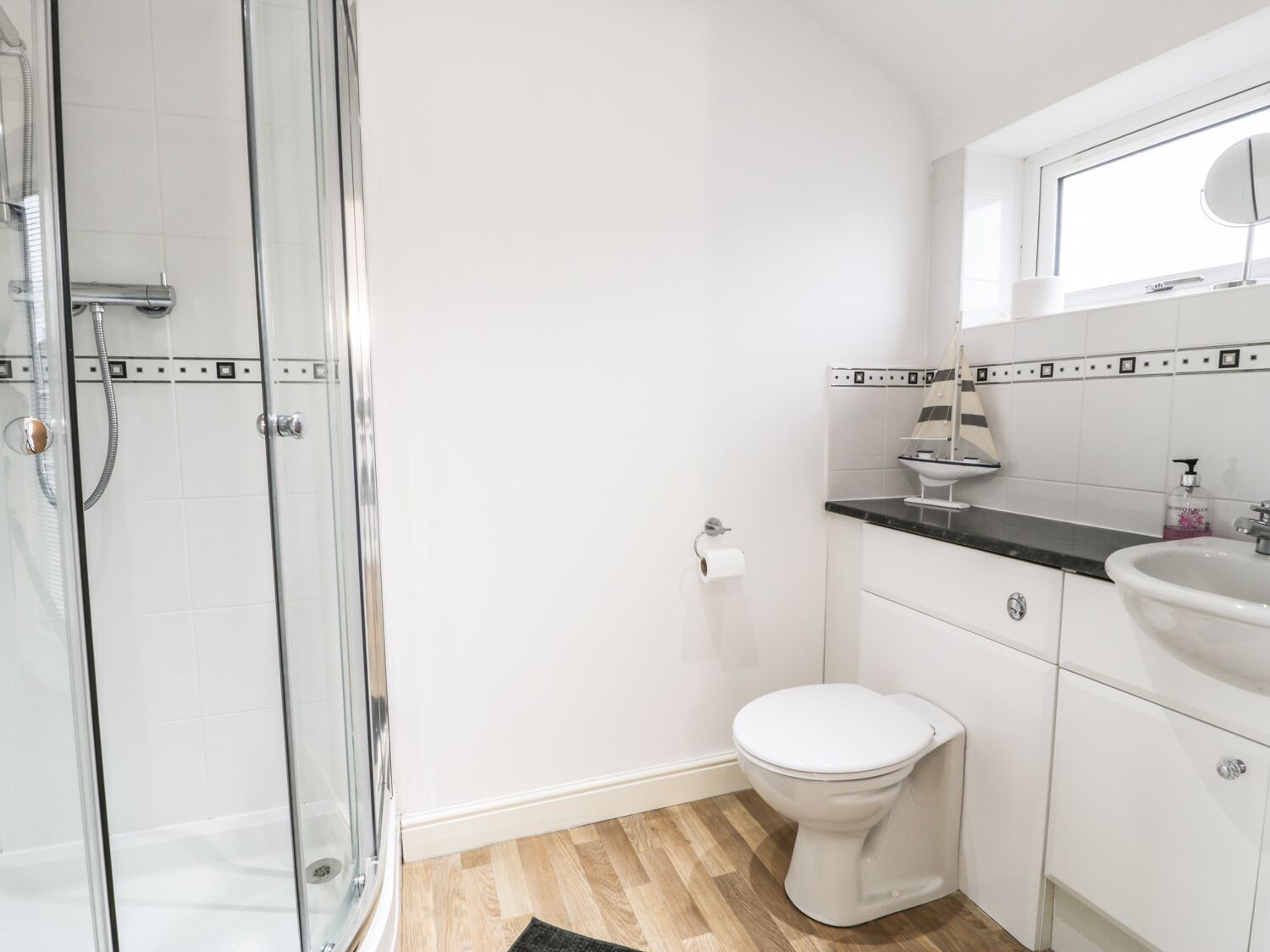 Een moderne badkamer met een douchecabine van glas, een toilet, een wastafel en een spiegel boven de wastafel.