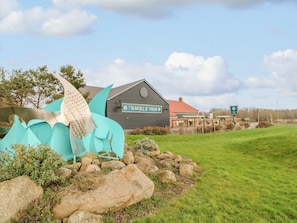 Experience the charm of The Ambleside Inn, surrounded by a beautifully maintained lawn and a striking sculpture of a fish.