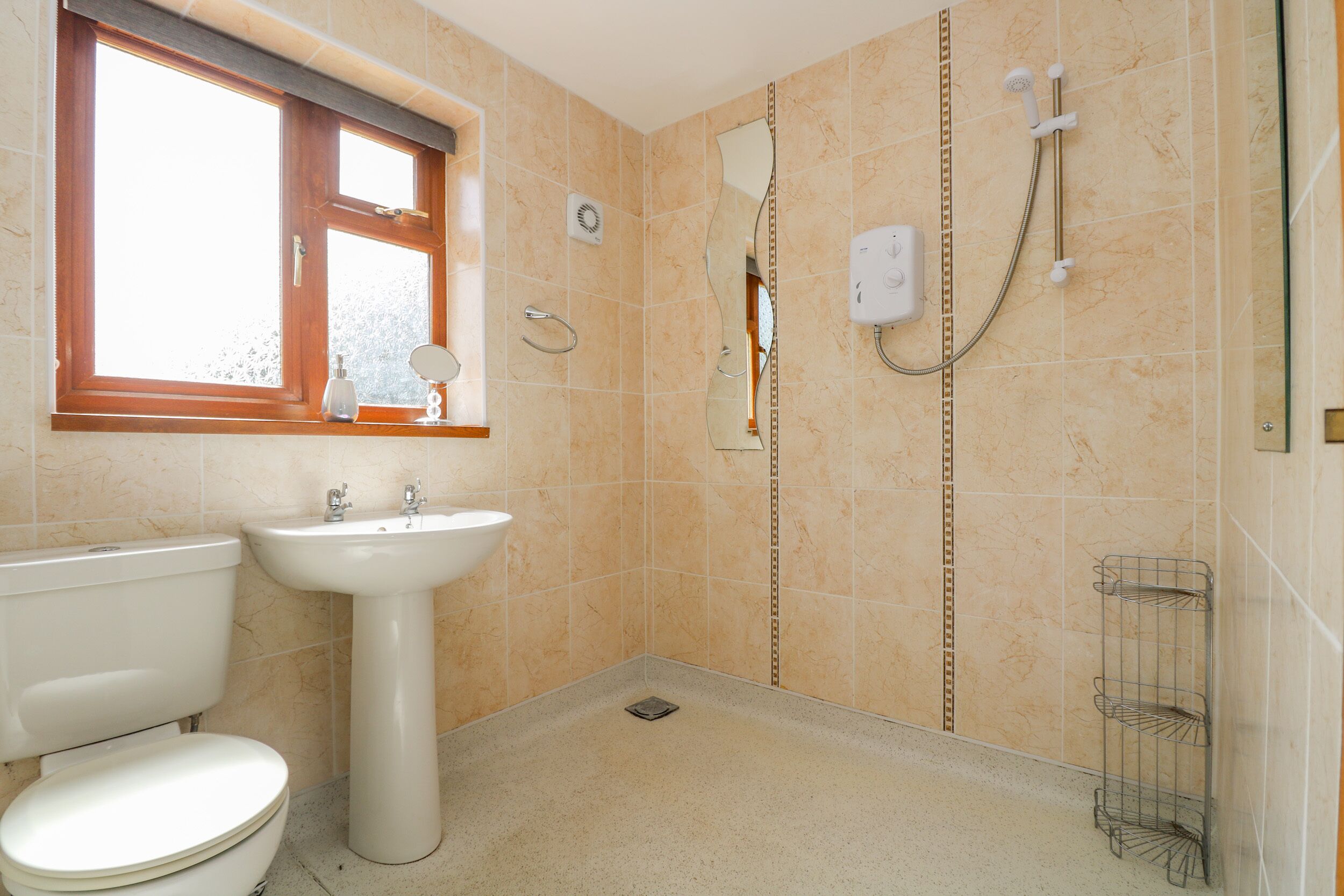 Un baño con inodoro, lavamanos, ducha y ventana.