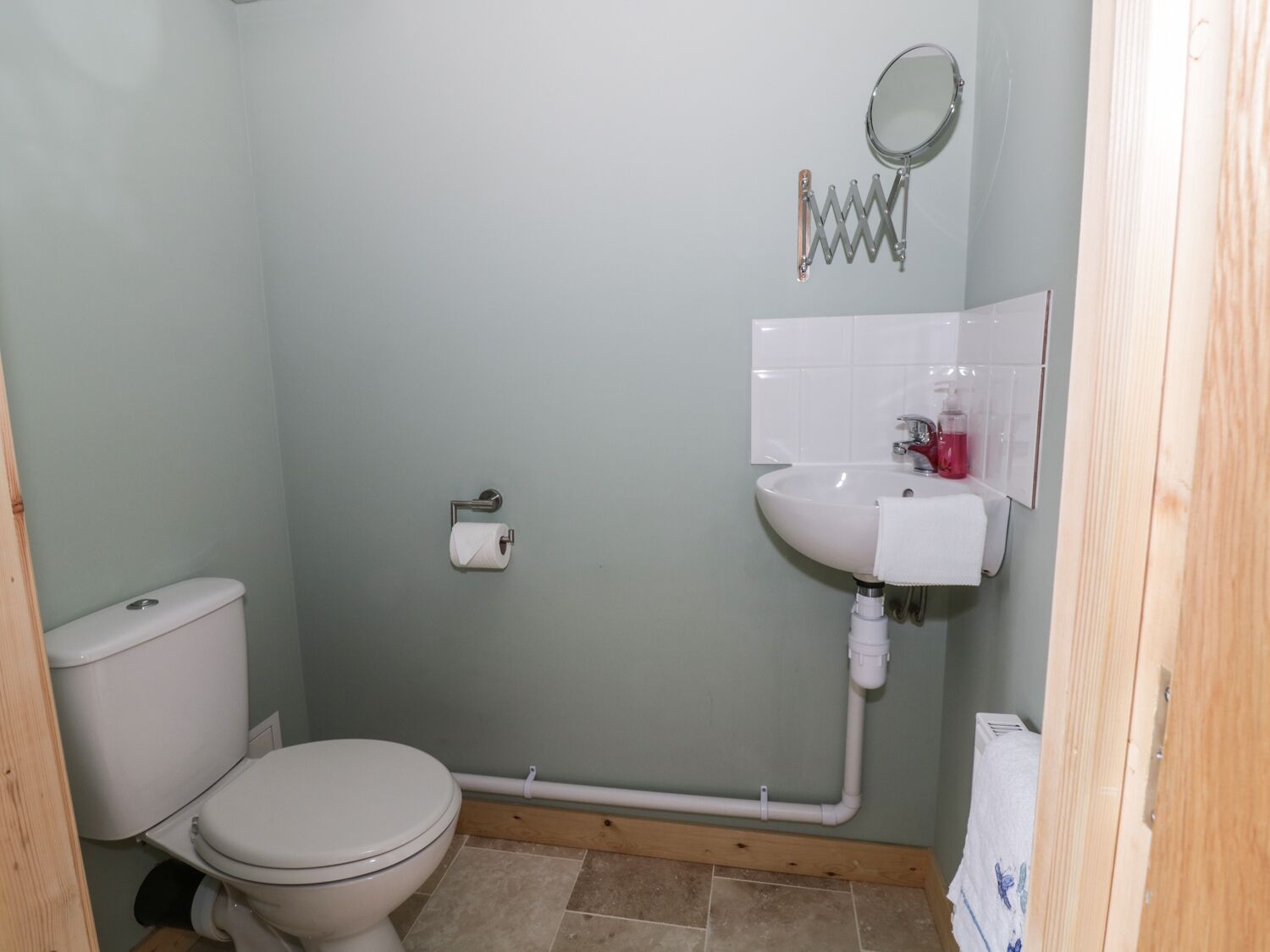 A small bathroom with a toilet, a sink, and a mirror.