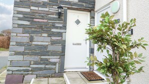 A stone building with a white door and a small plant in front.