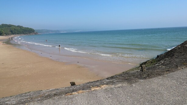 A beach with a clear sky, calm sea, and a rocky shoreline. - Sandy Bay House (Saundersfoot)
