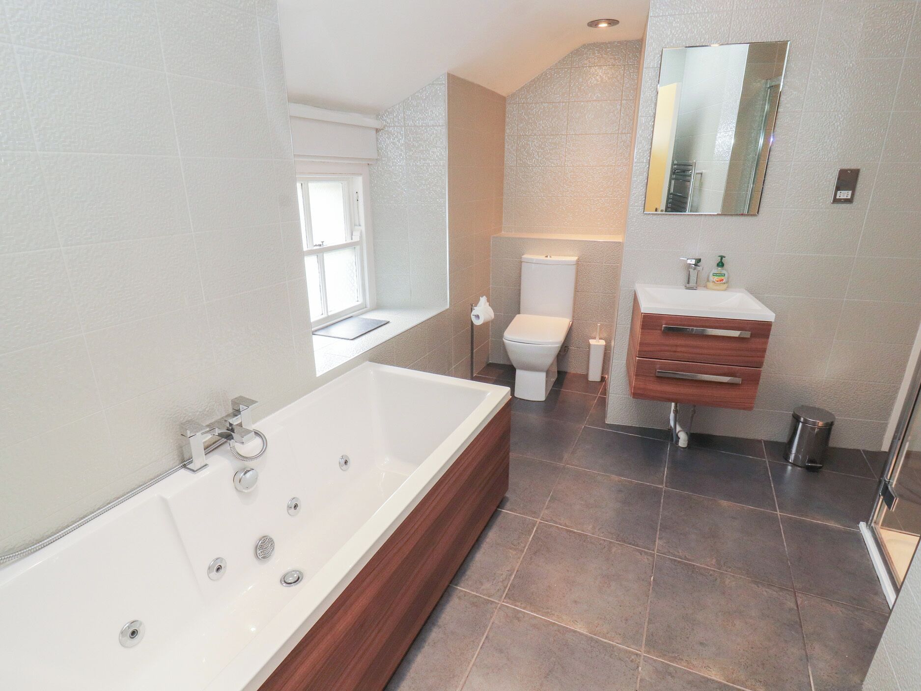 Une salle de bain moderne avec une baignoire sur pieds, des toilettes et un meuble-lavabo avec un miroir.