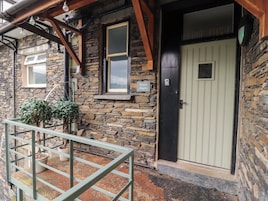 A stone building with a wooden porch, a door, and a small window.