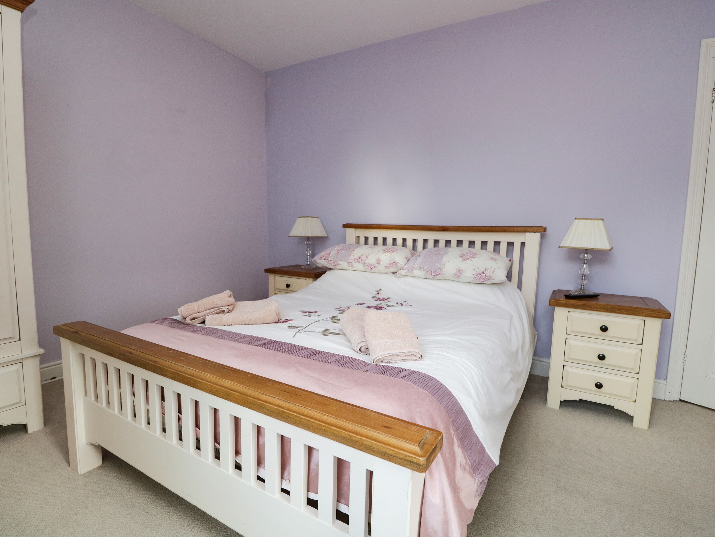 A bedroom with a wooden bed, two bedside tables, and a nightstand.