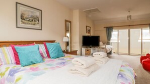 A hotel room with a large bed, a television, a window with curtains, and a painting on the wall. - Castlerigg (Keswick)
