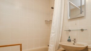A bathroom with a bathtub, a sink, and a mirror. - Castlerigg (Keswick)