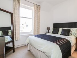 A bedroom with a bed, a bedside table, a lamp, and a window with curtains.