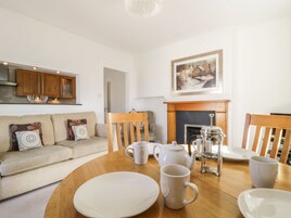 A living room with a sofa, a dining table with plates and cups, a fireplace, and wooden cabinets.