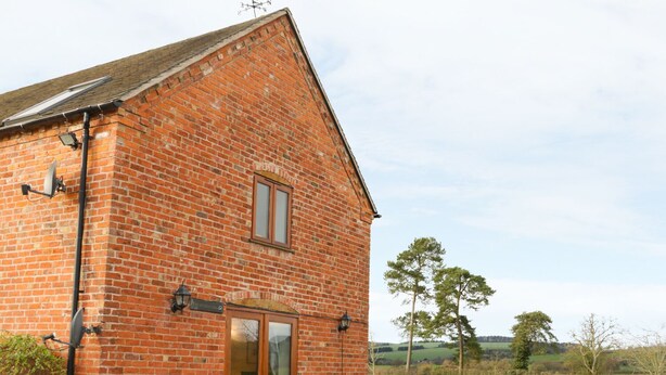 A brick building with a large glass door, a small window, and a satellite dish. - Ryelands Cottage (Much Wenlock)