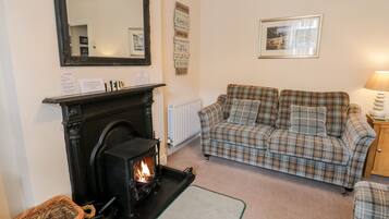 Ein gemütliches Wohnzimmer mit Kamin, Karomuster-Sofa und einem Spiegel.