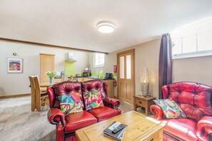 A spacious living room with a red leather sofa set, a wooden coffee table, and a dining area with a wooden table and chairs. - The Old Chapel (Hull)