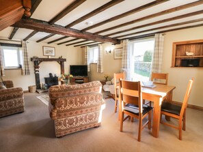 A cozy living room with a fireplace, a television, and a dining area with wooden furniture.