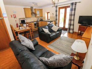 A living room with a sofa, a television, and a kitchen area with wooden cabinets and a stove.