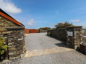 A gravel driveway leading to a stone building with a car parking sign.