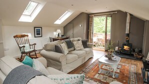 A cozy loft-style living room with a high ceiling, skylights, a fireplace, and a dining area. - The Barn (Shrewsbury)