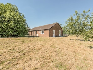 A single-story brick house with a sloped roof, a front porch, and a small front yard. - The Bungalow (Kidderminster)