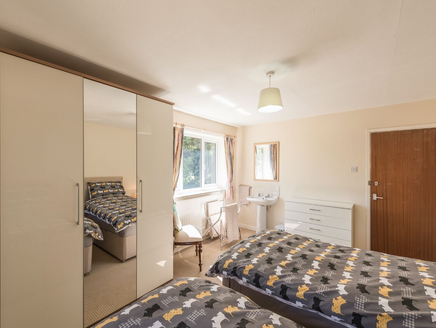 A bedroom with a bed, a wardrobe, a desk, and a window.