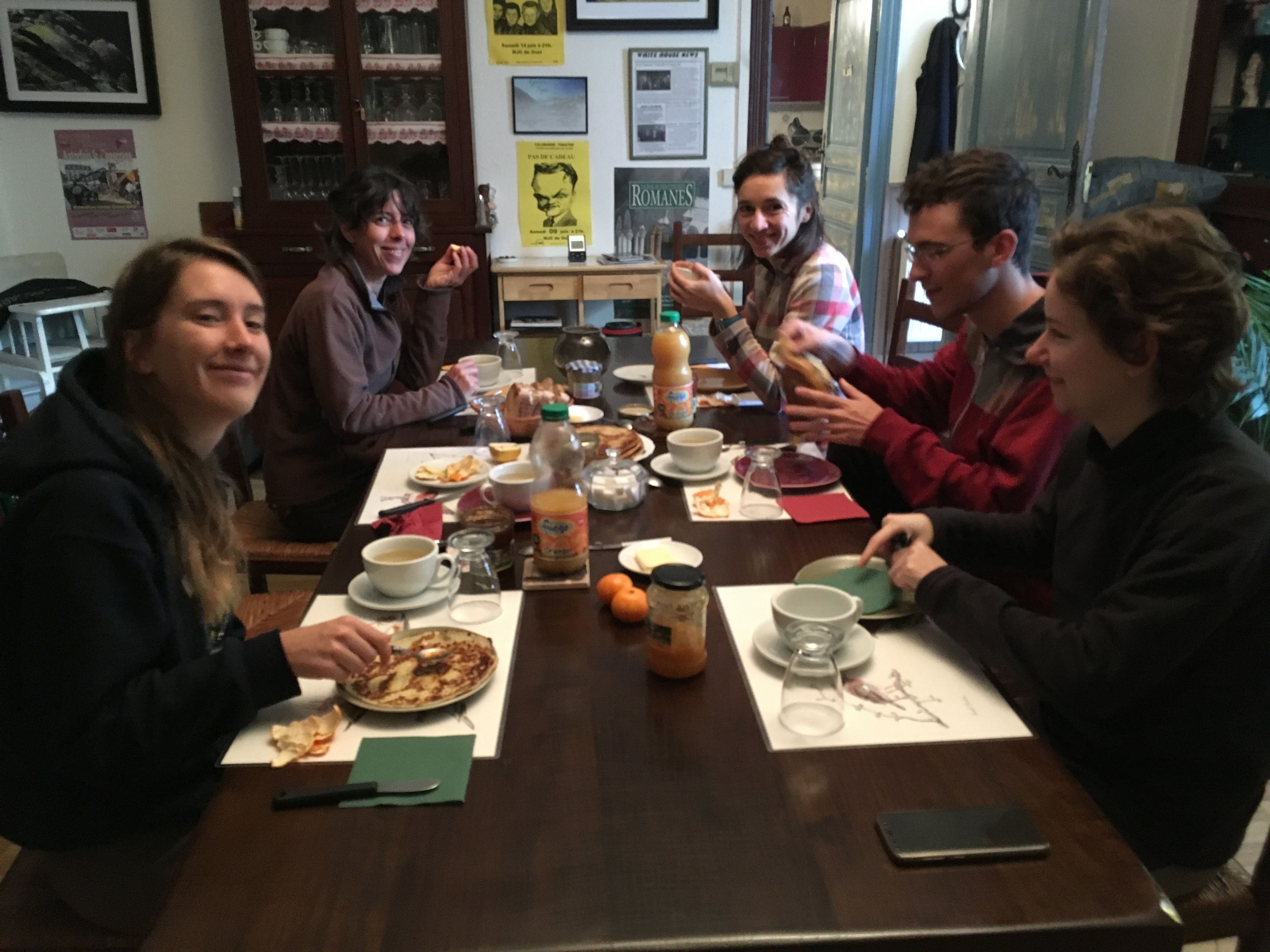 Un grupo de personas sentadas alrededor de una mesa de madera con comida y bebidas.