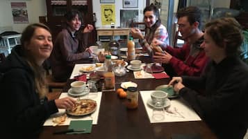 Un grupo de personas sentadas alrededor de una mesa de madera con comida y bebidas.