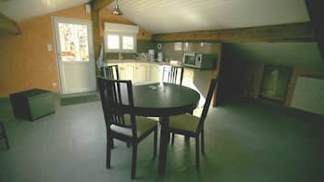 Un comedor con una mesa redonda y sillas, una cocina equipada y una ventana con vistas.