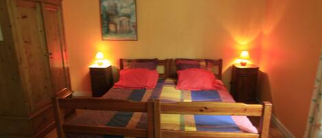 A room with two bunk beds, wooden wardrobe, and two bedside lamps.