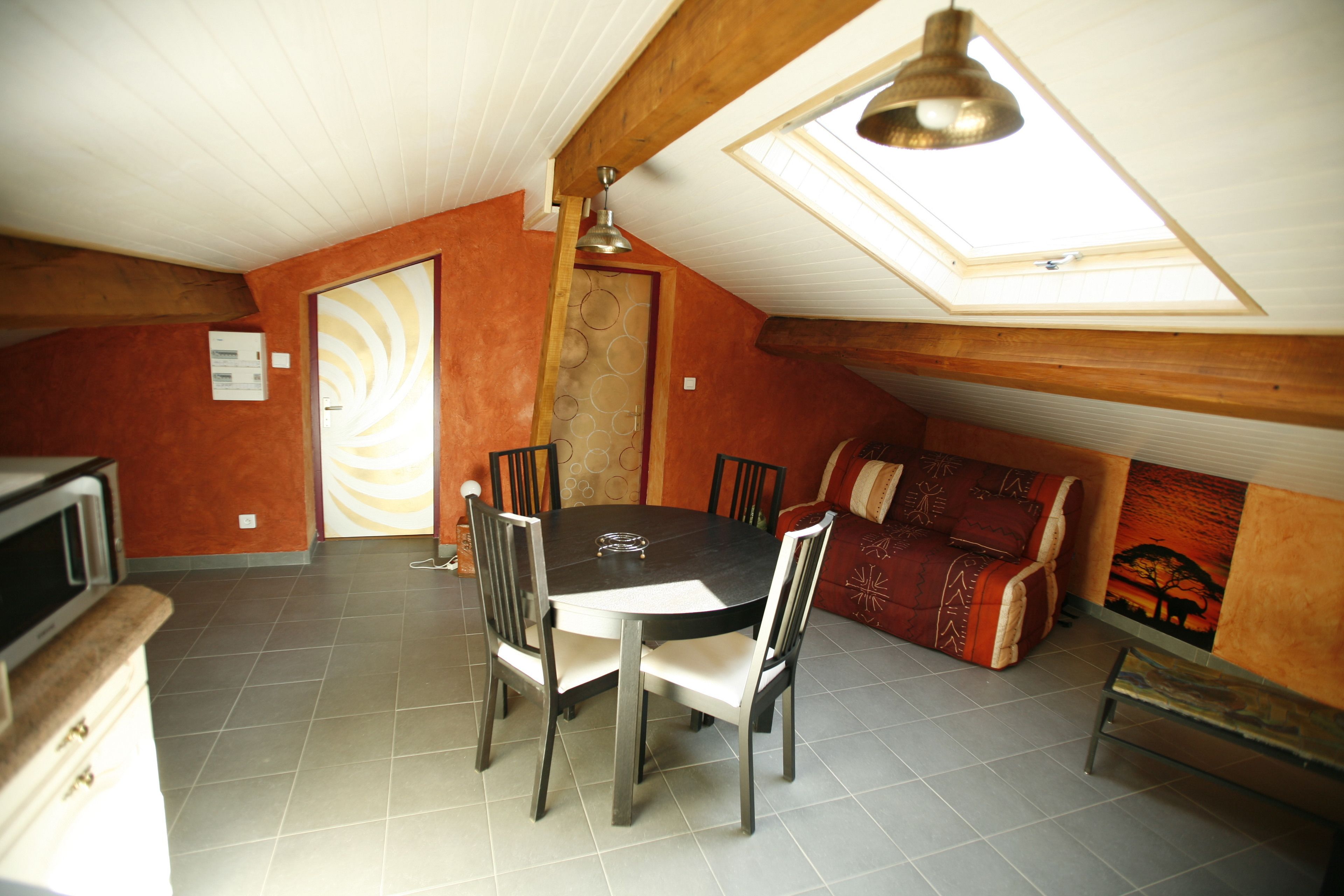 A dining area with a round table and chairs, a sofa, and a ceiling with a skylight.