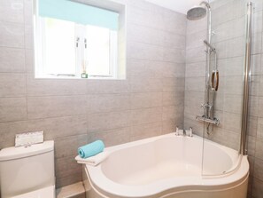 A modern bathroom with a freestanding bathtub, a showerhead, and a window with a view.