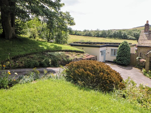 A residential property with a garden, a house with a flat roof, and a stone wall.