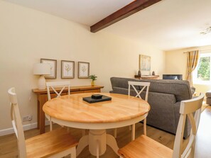 A dining area with a round wooden table and chairs, a sofa, a TV, and framed artwork on the wall. - The Milking Parlour (York)
