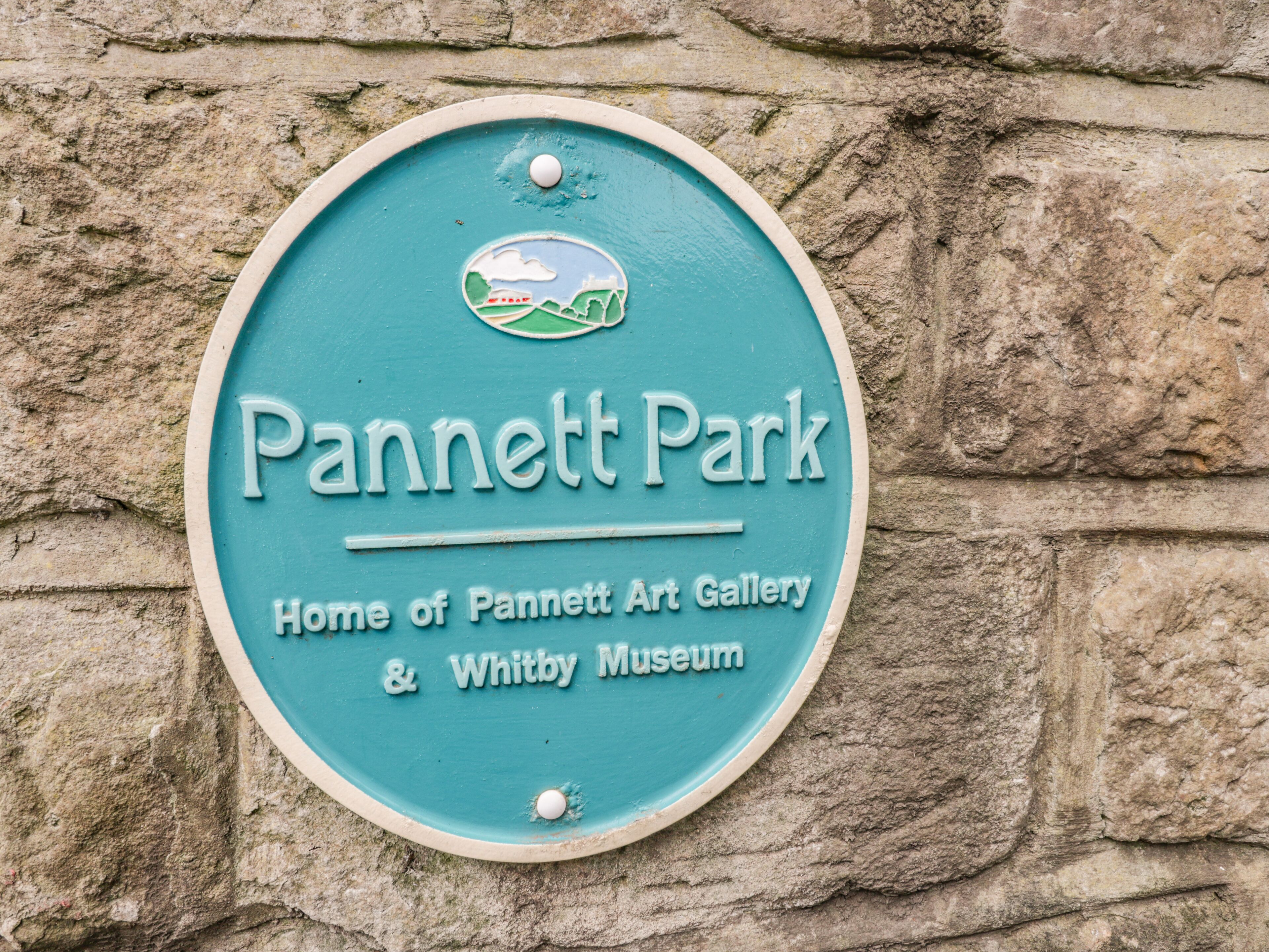 Een rond bord met de tekst 'Pannett Park' en de vermelding 'Thuis voor Pannett Art Gallery & Whitby Museum'.