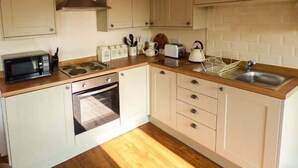 A compact kitchen with a microwave, toaster, kettle, and wooden countertop. - The Old Corn Store (Keighley)