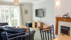 Una sala de estar con sofá, mesa de madera, televisor y chimenea.
