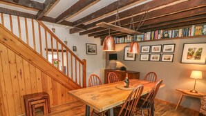 Ein Essbereich mit Holztisch und Stühlen, einer Treppe und einem Bücherregal voller Bücher.