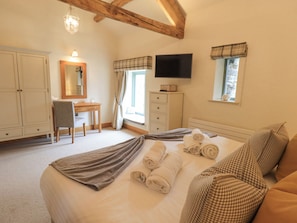 Relax in a spacious bedroom with a large bed, desk, and TV, perfect for unwinding.