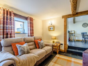 Relax in this inviting living room with a sofa, side table, and lamp, surrounded by a large window and a framed picture.