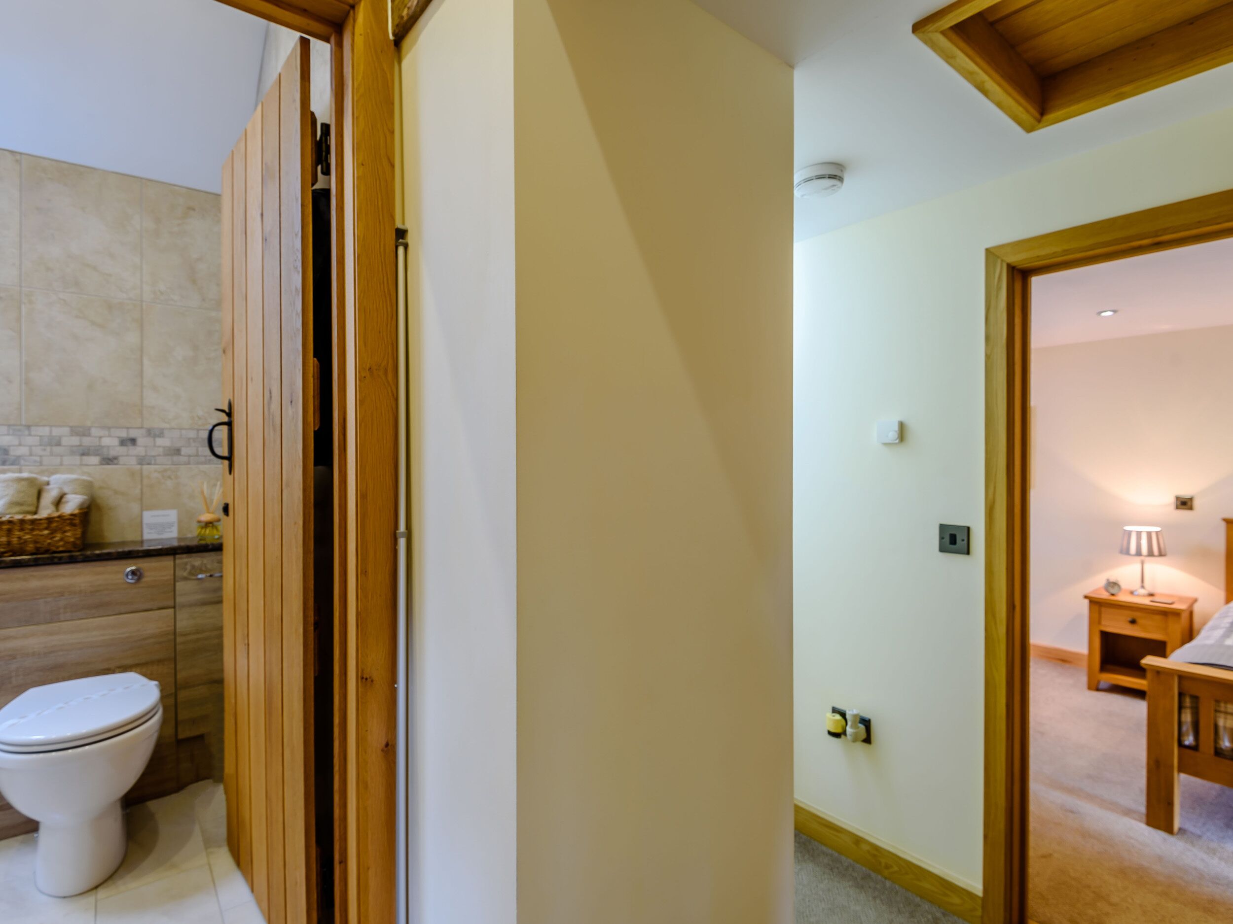 Un baño con inodoro, muebles de madera y salpicadero de azulejos.