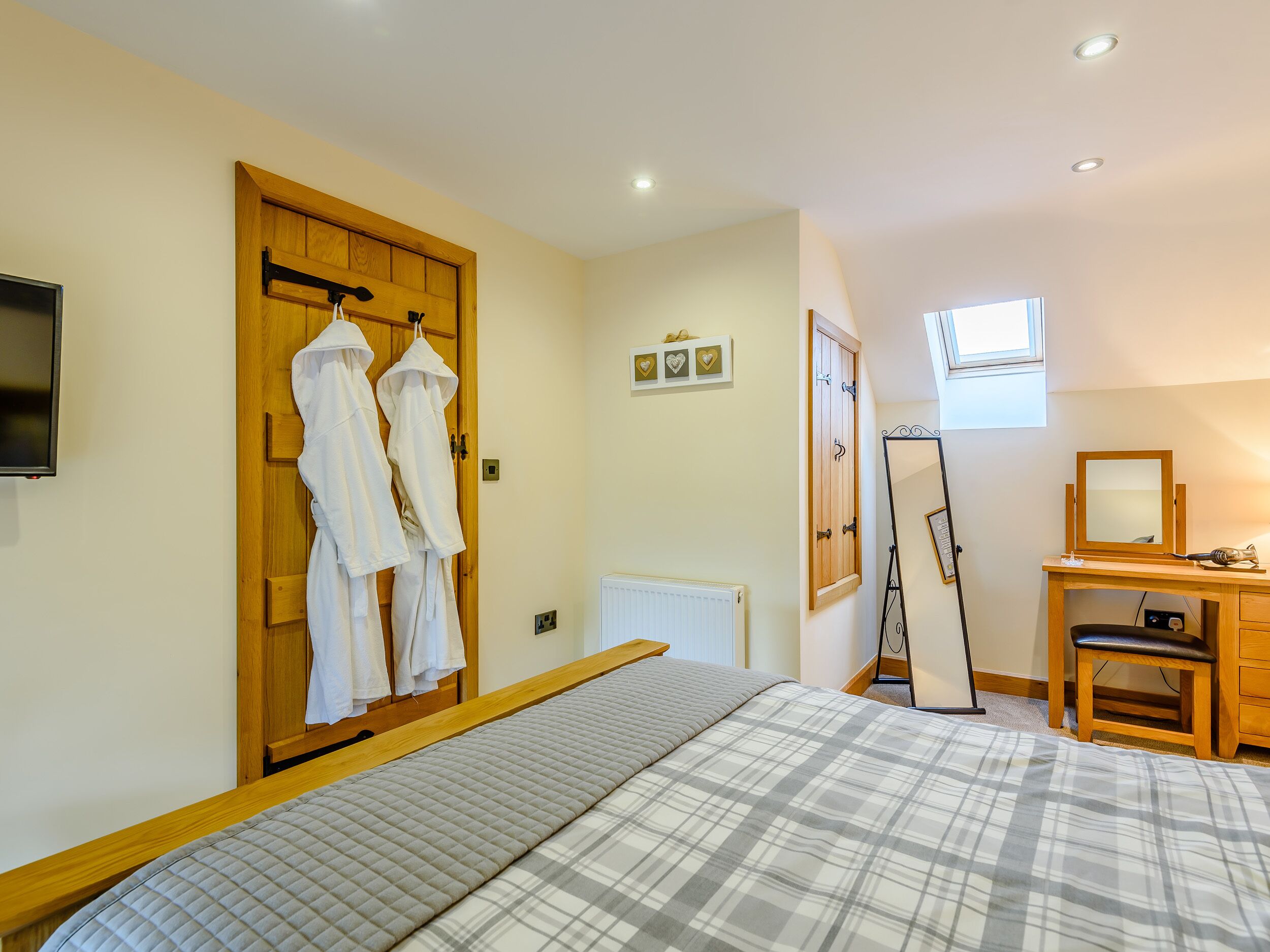 A bedroom with a bed, wooden wardrobe, a mirror, and a desk.