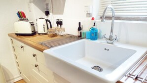 A kitchen with a white sink, a toaster, a kettle, and various kitchen utensils on the countertop.