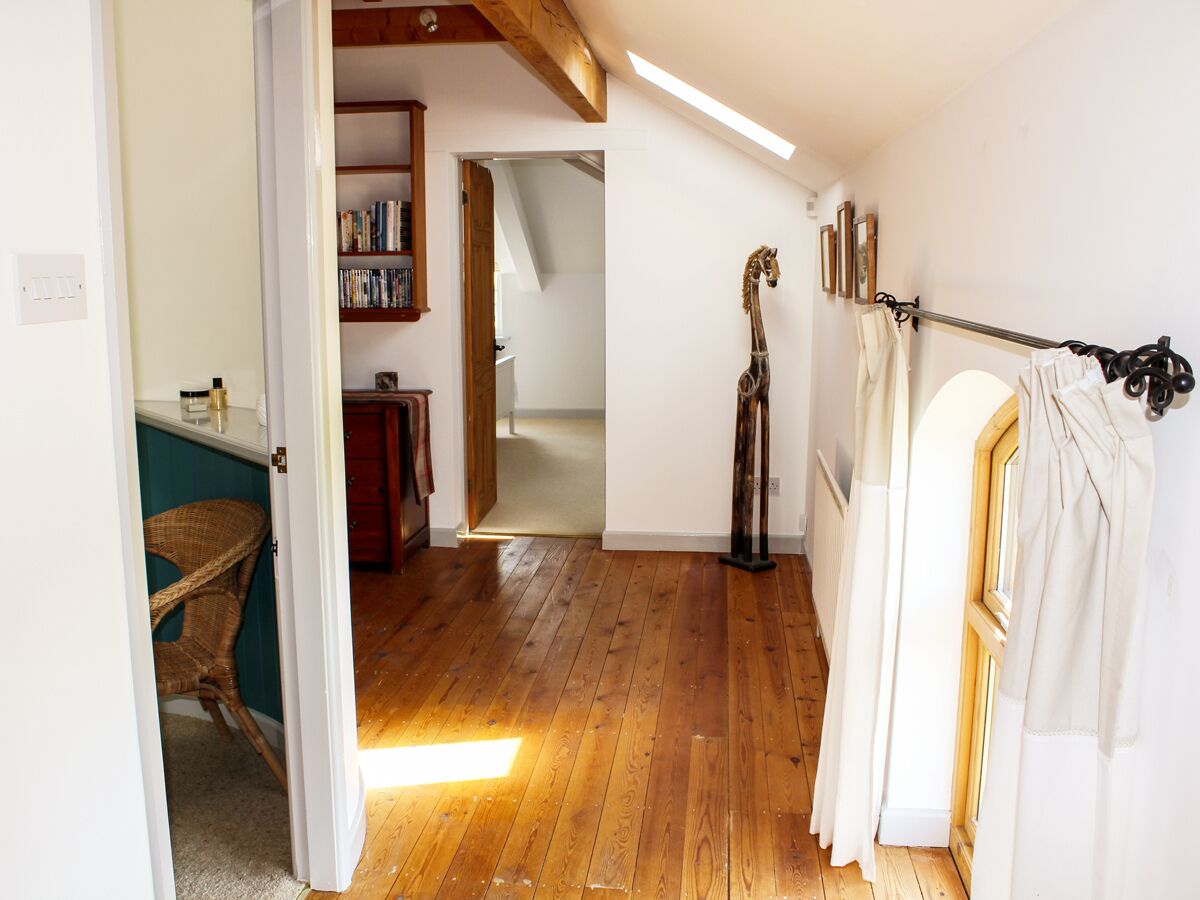 A room with wooden flooring, a bookshelf, a giraffe sculpture, and a window with curtains.