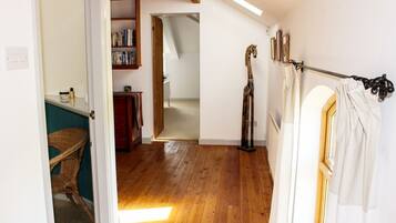 A room with wooden flooring, a bookshelf, a giraffe sculpture, and a window with curtains.