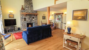 A cozy living room with a stone fireplace, a television, and a blue sofa.