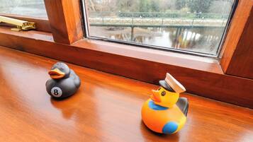 Dos patitos de goma sobre una superficie de madera junto a una ventana.