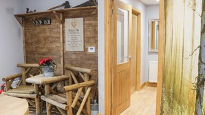 A rustic wooden wall with a sign listing life rules, a wooden bench, and a door leading to another room. - Woodman's Lodge (Nantwich)
