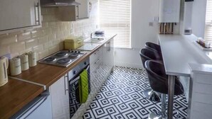 A modern kitchen with a gas stove, white cabinets, and a patterned floor. - Flat 3 (Bridlington)