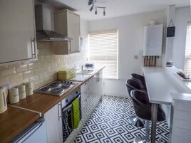 Una cocina moderna con estufa a gas, armarios blancos y piso estampado.