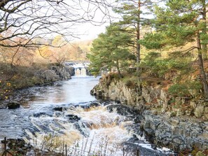 A river flowing through a rocky landscape with a waterfall in the distance.