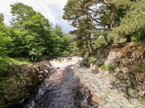 A stone bridge over a flowing river, surrounded by lush greenery and trees.