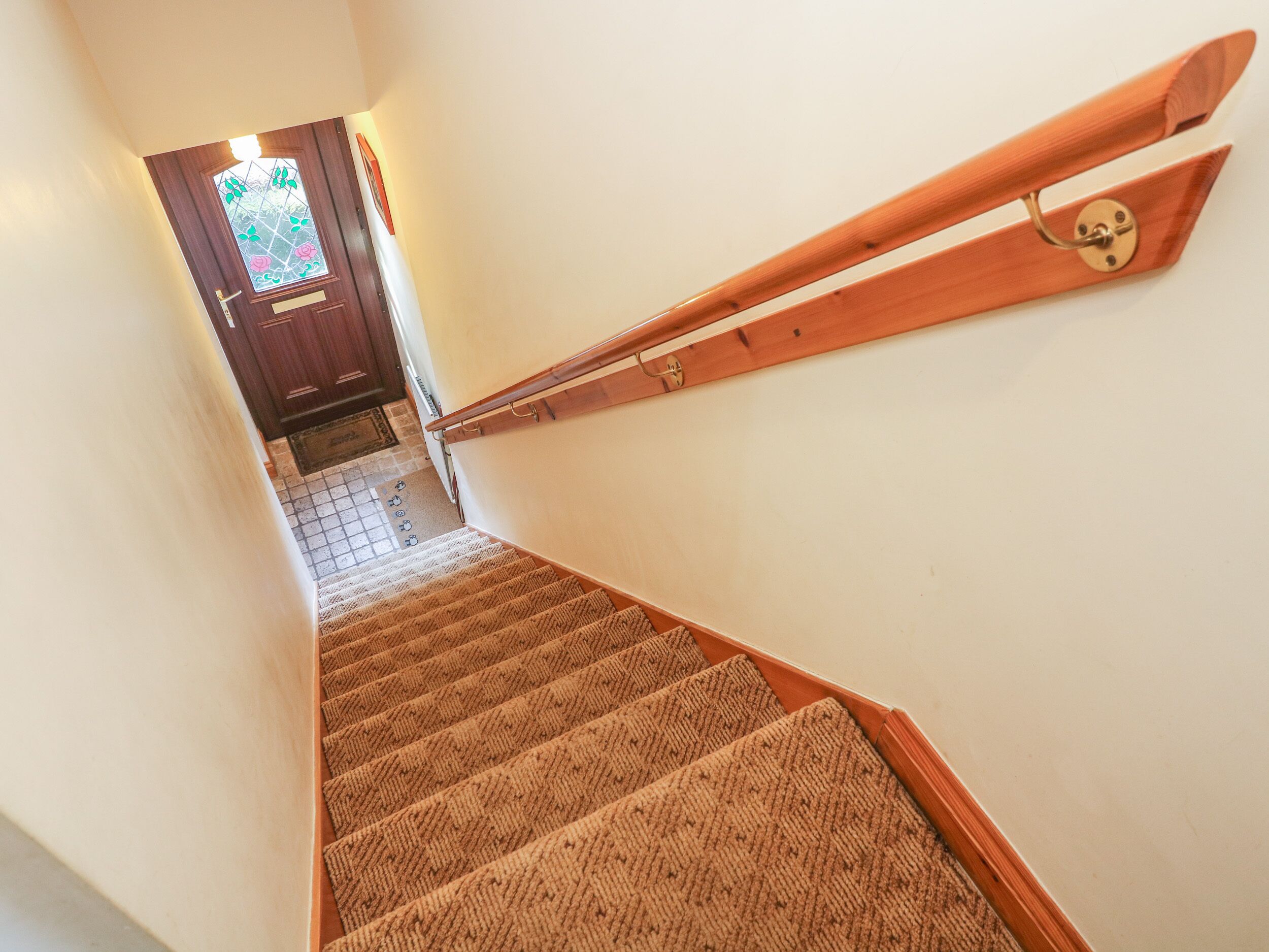 A carpeted staircase with wooden handrails and a door at the top.