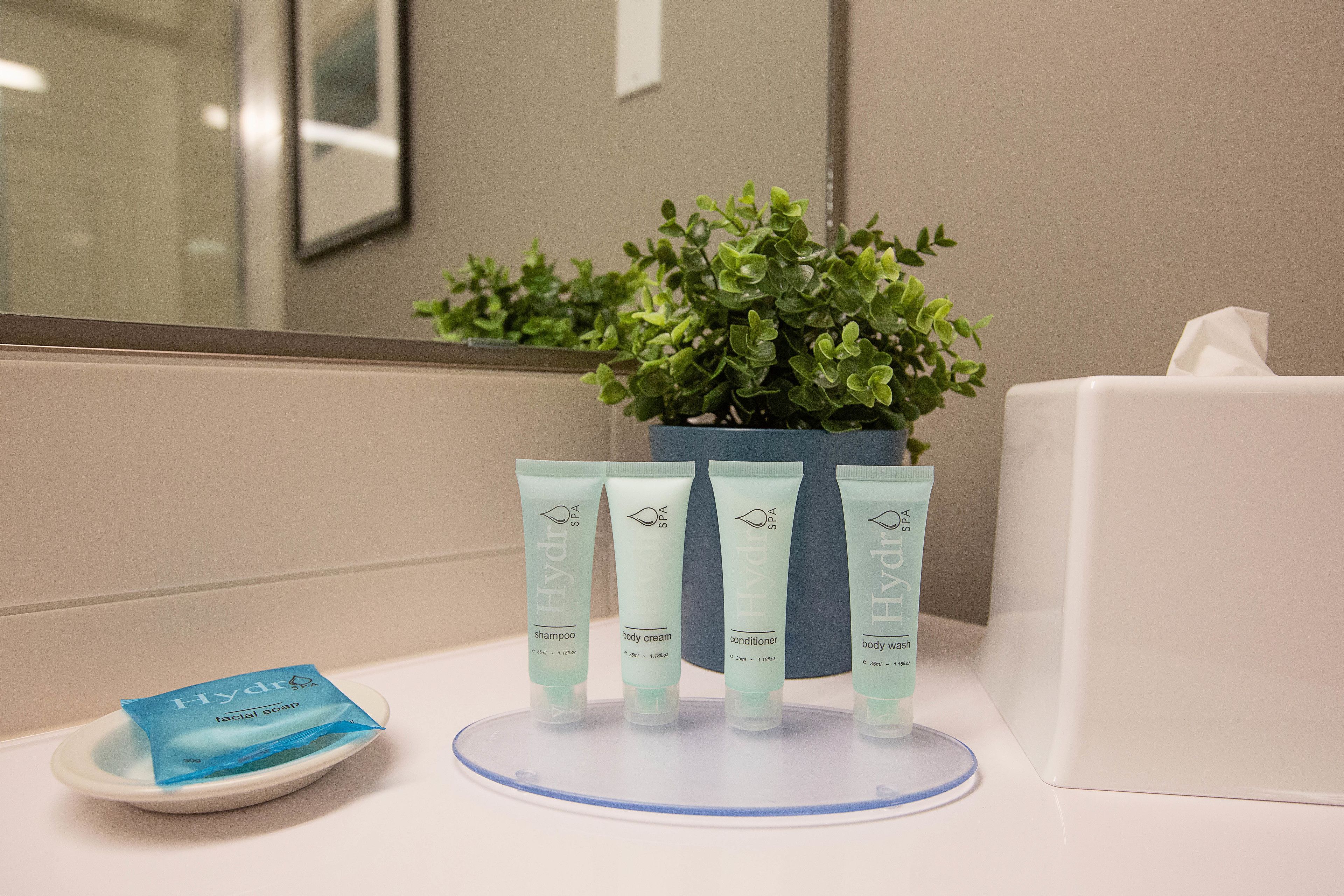 Una encimera de baño con una planta en maceta, una caja de pañuelos y cuatro productos para el cuidado de la piel Hydra.